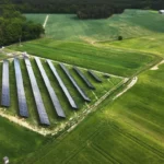 Widok z góry na farmę fotowoltaiczną ulokowaną w pobliżu zabudowań wiejskich – wykorzystanie energii słonecznej w regionie rolniczym.