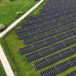 Widok z drona na panele fotowoltaiczne ustawione w równych rzędach w krajobrazie rolniczym – zielona energia przyszłości.